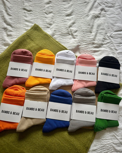 Assorted pairs of socks with 'BAMBS & BEAU' labels on a textured surface.